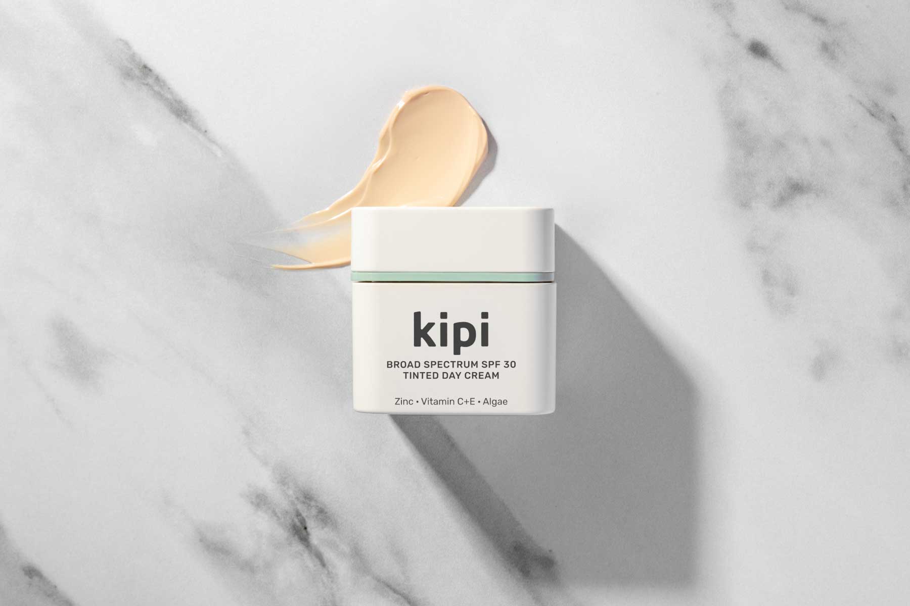Kipi Broad Spectrum SPF 30 Tinted Day Cream jar on a marble background