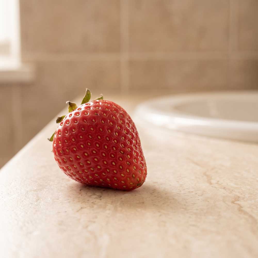Single strawberry on a marble surface with a blurred background