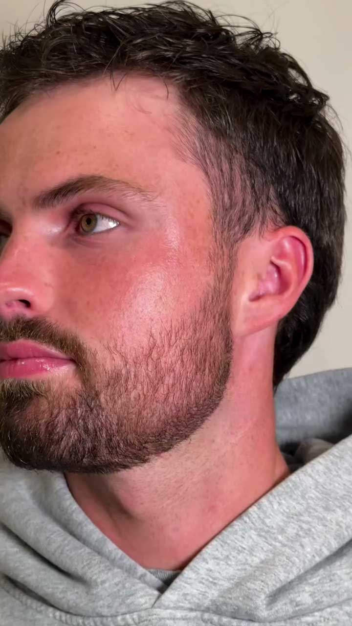 Close-up of a man with a beard and short hair wearing a gray hoodie.
