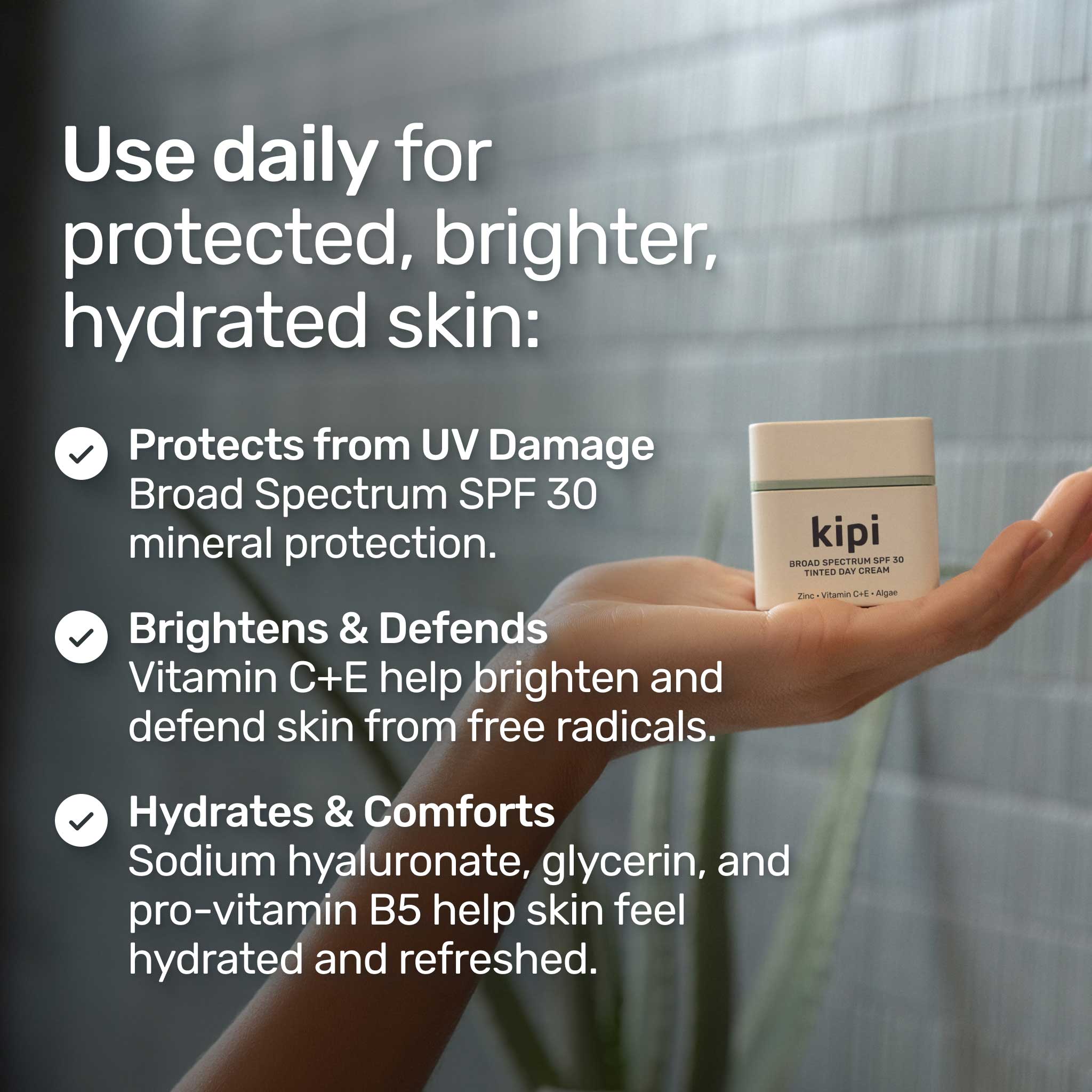 Hand holding a kipi skincare product with text about its benefits in a bathroom setting.