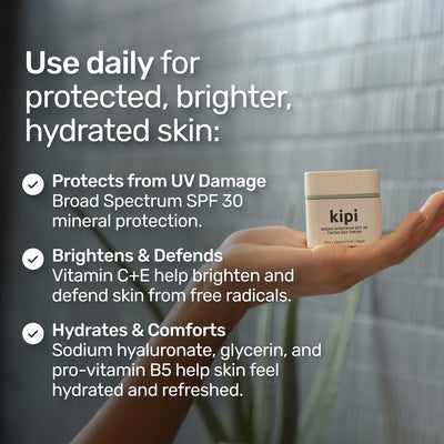 Hand holding a kipi skincare product with text about its benefits in a bathroom setting.