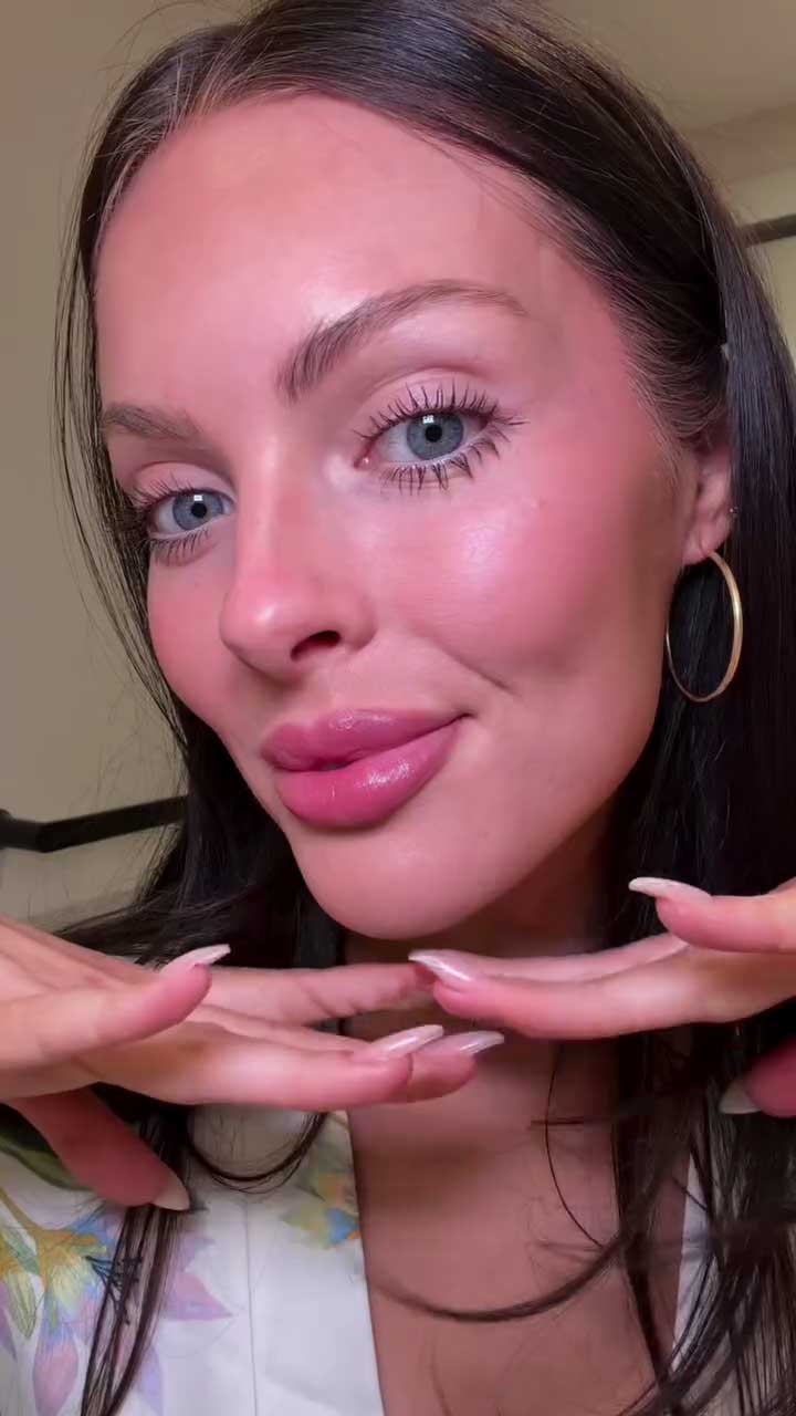 Close-up of a person with hands framing their face against a neutral background