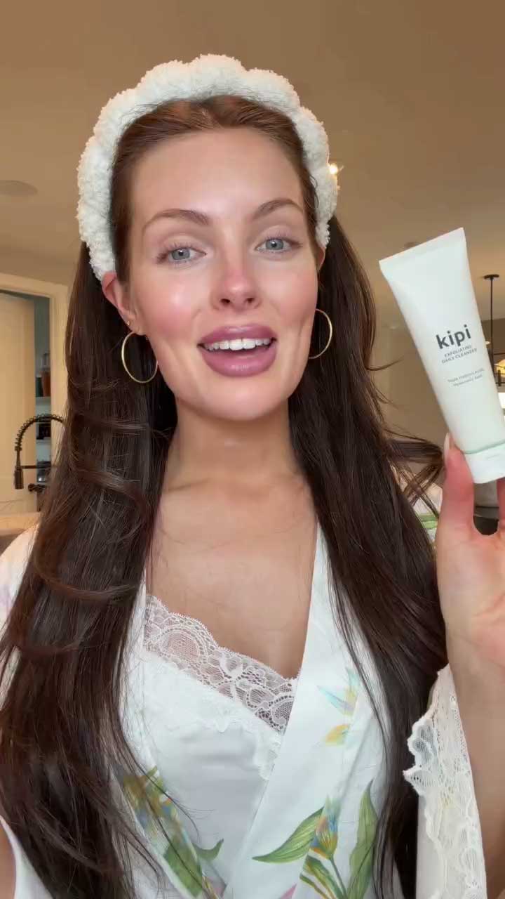 Woman holding a skincare product with 'kipi' branding in a casual setting.