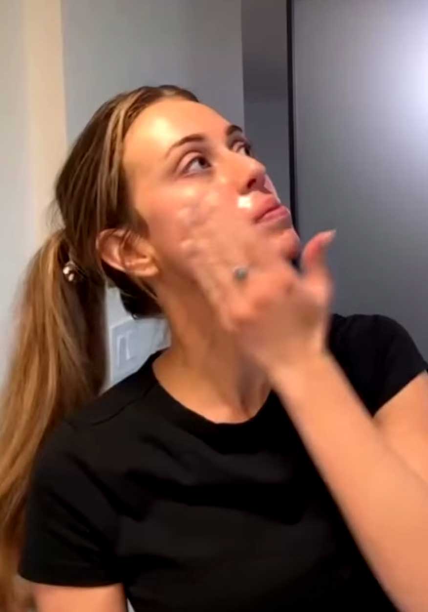Woman washing her face at sink, using skin cleanser.